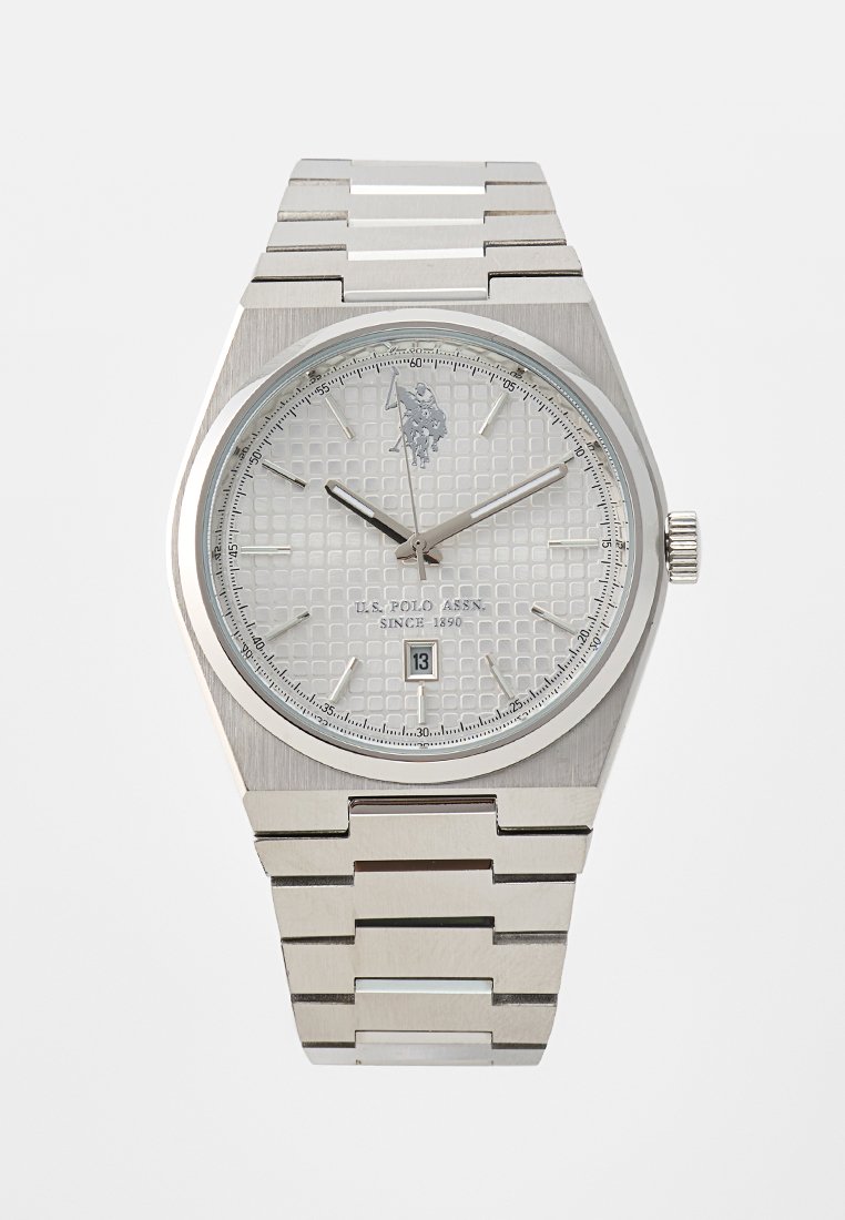 Montre en acier inoxydable argenté avec un cadran blanc texturé, des aiguilles argentées, un affichage de date et un design de boîtier hexagonal. Elle est équipée d'un bracelet en maillons métalliques.
