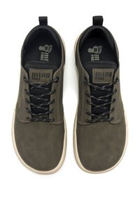 Zapatillas verde oliva con una textura suave, cordones negros y una solapa en el talón. Presentan una plantilla acolchada y una suela de color claro.
