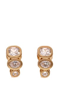 Guldtonede øreringe med tre klare, facetterede krystaller i forskellige størrelser i et stablet design, med teksturerede detaljer omkring indstillingerne.