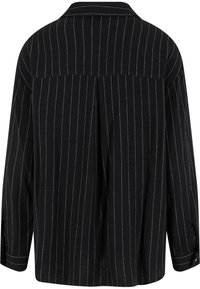 Must valge vertikaalsete triipudega triiksärk, millel on klassikaline krae, lõdvestunud lõige ja volt detail tagaküljel. Pehme kangatundega, pika varrukaga.