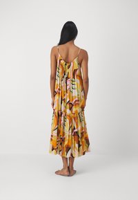 Maxi dress featuring a colorful abstract print with yellow, orange, pink, and green tones. Flowy fabric with adjustable spaghetti straps and a ruffled hem.
