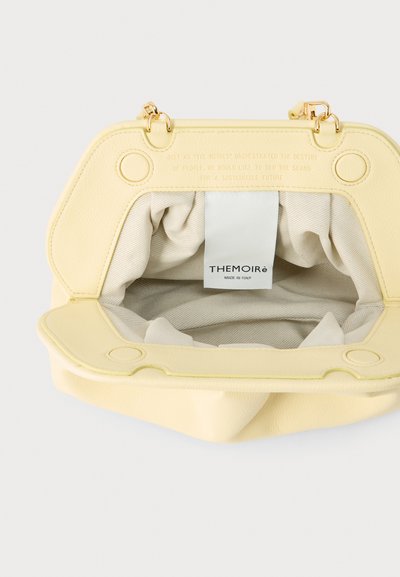 Sac à main en cuir jaune avec cadre ouvert montrant l'intérieur en tissu beige et une étiquette blanche portant l'inscription "THEMOIRè Made in Italy."