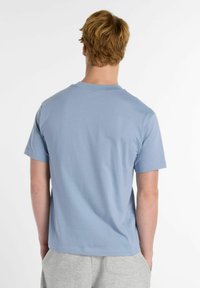 T-shirt bleu clair à manches courtes avec un col rond et une texture douce. Design minimaliste sans motifs ni accents visibles.
