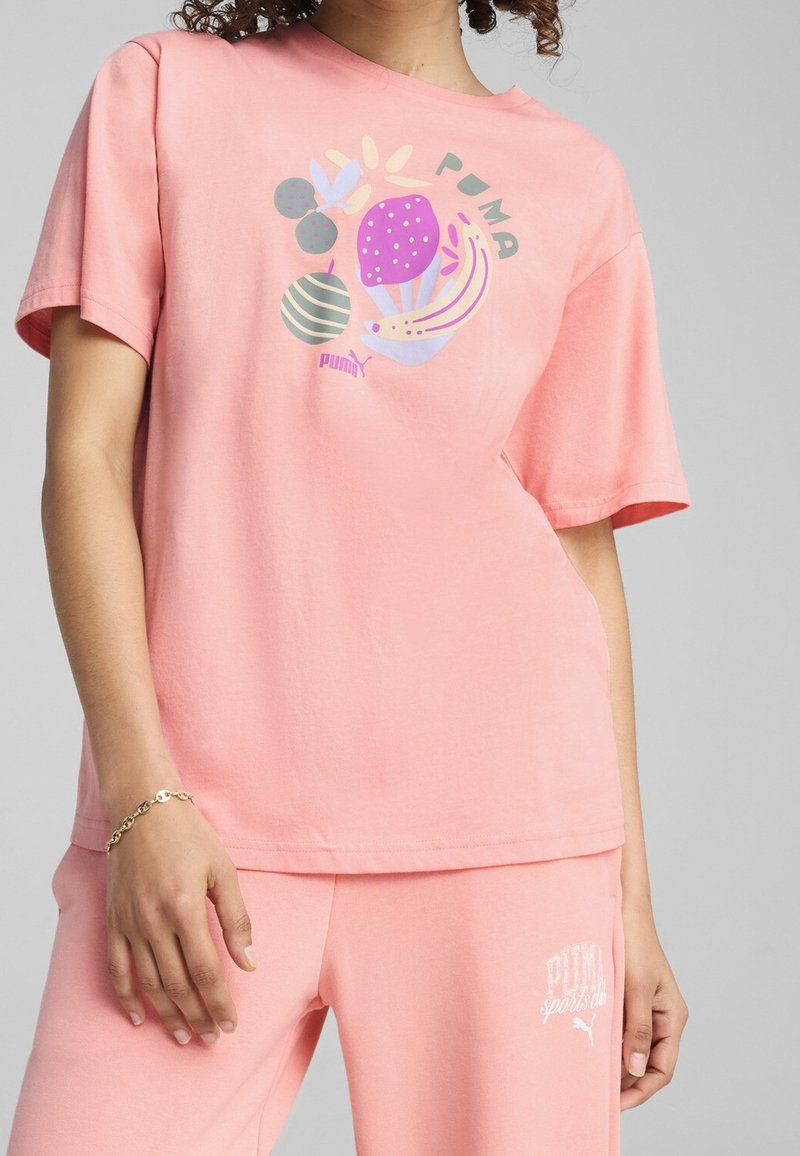 Rosa bomulls t-shirt med korta ärmar och rund halsringning. Har färgglada fruktdesign och "PUMA" logotyp i stiliserad text.