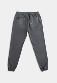 Grijze elastische broek met twee achterzakken en een gebogen naaddetail. Heeft een turquoise accentsteek op één van de zakken.