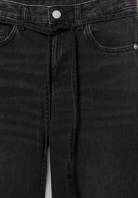 Pantalon en denim noir avec bouton à l'avant, passants pour ceinture et une ceinture en tissu nouée qui pend au centre de la taille à l'avant.