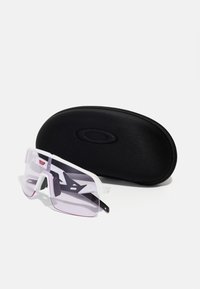 Gafas de sol con montura blanca transparente y lentes tintados de rosa. Incluye un estuche rígido negro con un logotipo. Diseño anguloso con almohadillas nasales ajustables.