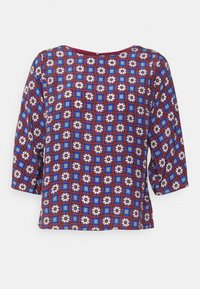 Blouse multicolore dotée d'un motif en grille avec des fleurs bleues, rouges et blanches. Manches courtes et amples, et col rond.