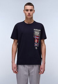 Marineblå bomulds T-shirt med et grafisk design på brystet, der viser landeflag og teksten "SINCE 1987." T-shirten har korte ærmer og rund halsudskæring.