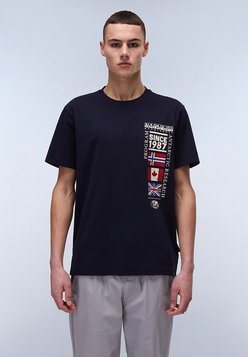 Marineblå bomulds T-shirt med et grafisk design på brystet, der viser landeflag og teksten "SINCE 1987." T-shirten har korte ærmer og rund halsudskæring.