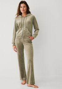 Velvet loungewear set in gedempt groen, met een rits-hoodie met voorzakken en flared broek met een gladde textuur.