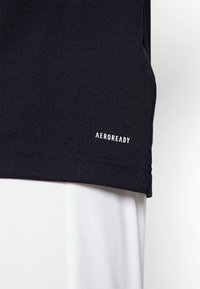 Svart idrottströja med AEROREADY-märkning i vitt vid nederkanten, tillverkad av ett slätt, fukttransporterande material.