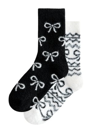 To bløde sokker, en sort med hvide sløjfe mønstre og en hvid med sorte geometriske og spiral design.