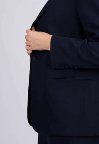 Blazer ajusté bleu marine en tissu structuré avec fermeture à un bouton, poches latérales et revers élégants.