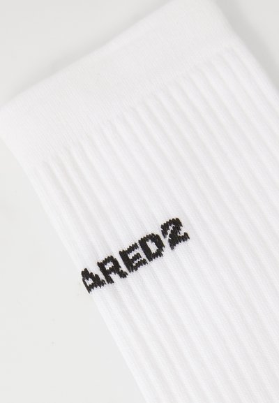 Weißes Sockenset mit vertikaler Rippstruktur, versehen mit dem schwarzen "RED2"-Logo, das an der Seite gestickt ist. Das weiche Material sorgt für ein angenehmes Tragegefühl.