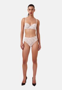 Spids lingerie sæt med en blød beige bh med bøjle og matchende højtaljede trusser, begge med indviklede blomster mønstre.