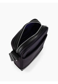 Schwarze Nylon-Tasche mit strukturiertem Finish, doppelte Reißverschlussöffnung und einem separaten Fach. Das Innere ist mit einem kontrastierenden lila Futter ausgestattet.