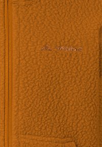 Fleece jack in oranje met een gestructureerd oppervlak, voorzien van een rits en een reliëflogo op de linkerkant van de borst. Zacht, warm materiaal.