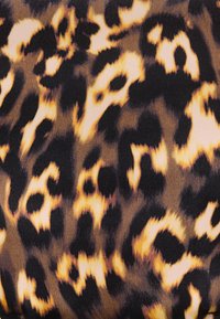 Ύφασμα με ακανόνιστο μοτίβο λεοπάρ σε μαύρο, καφέ και μπεζ, που παρουσιάζει μαλακή υφή και κοντινή θέα του σχεδίου.