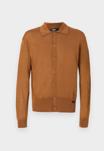 Καφέ cardigan με κουμπιά και μακριά μανίκια, γιακά, ριμπ στα μανίκια και στο τελείωμα, και μία μικρή μαύρη ετικέτα κοντά στο κάτω τελείωμα.