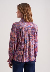 Bunt gemusterte Bluse im Paisleydesign mit hohem Kragen, gefaltetem Rücken und taillierten Ärmeln. Aus leichtem, strukturiertem Stoff gefertigt.