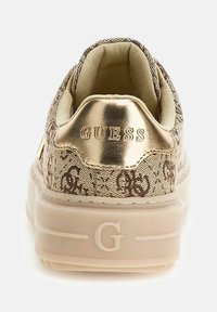 Adidași maro cu un model, având un accent metalizat aurie la călcâi. Au un guler căptușit și o talpă din cauciuc de culoare deschisă cu detalii ale logo-ului.