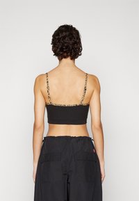Top corto nero con spalline sottili e dettagli in stampa leopardata. Realizzato in materiale morbido, ha un design aderente e uno stile minimalista.