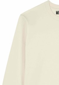 T-shirt à manches longues de couleur crème, fabriqué en coton doux, avec un col rond et des détails de couture minimalistes.