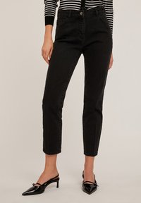 Jeans negros de tiro alto con un ajuste slim y una longitud recortada, hechos de denim, con bolsillos frontales y un cierre de botón metálico.