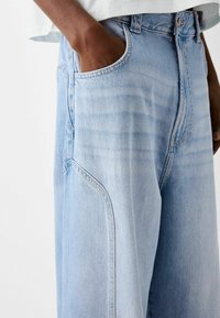 Ljusblå denimbyxor med hög midja, som har en framficka och en slät textur, designade med subtila blekningar och skräddarsydda sömmar.