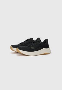 Chaussures de sport noires avec un dessus en tissu texturé, une semelle intermédiaire blanche et une semelle extérieure en caoutchouc couleur gomme. Présente un design à lacets et un accent de logo.