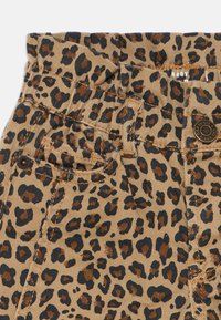 Leopardo raštas ant šviesiai rudos fono, su juodais ir rudais taškais. Įtraukta įvaržtų ir siūlių detalės. Kelnės stiliaus dizainas.