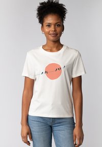Weißes Baumwoll-T-Shirt mit einem zentralen Grafikdruck eines Pfirsichkreises, auf dem Vögel auf einer dünnen Linie sitzen. Rundhalsausschnitt und kurze Ärmel.