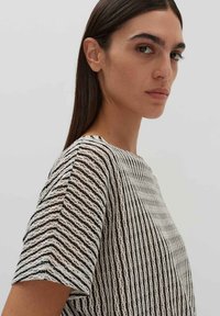 Gestreepte korte mouwen top in wit en zwart, met een gestructureerde stof, een losse pasvorm, ronde halslijn en details aan de zijnaden.