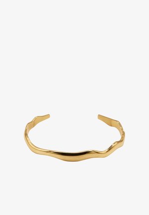 Bracelet en métal doré avec une forme ondulée et organique. Fini lisse et brillant avec des extrémités effilées pour un port facile.