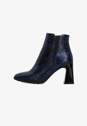 Niebiesko-czarny botek za kostkę z teksturowanym wykończeniem, spiczastym noskiem, wysokim słupkowym obcasem oraz elastyczną boczną wstawką ułatwiającą zakładanie.