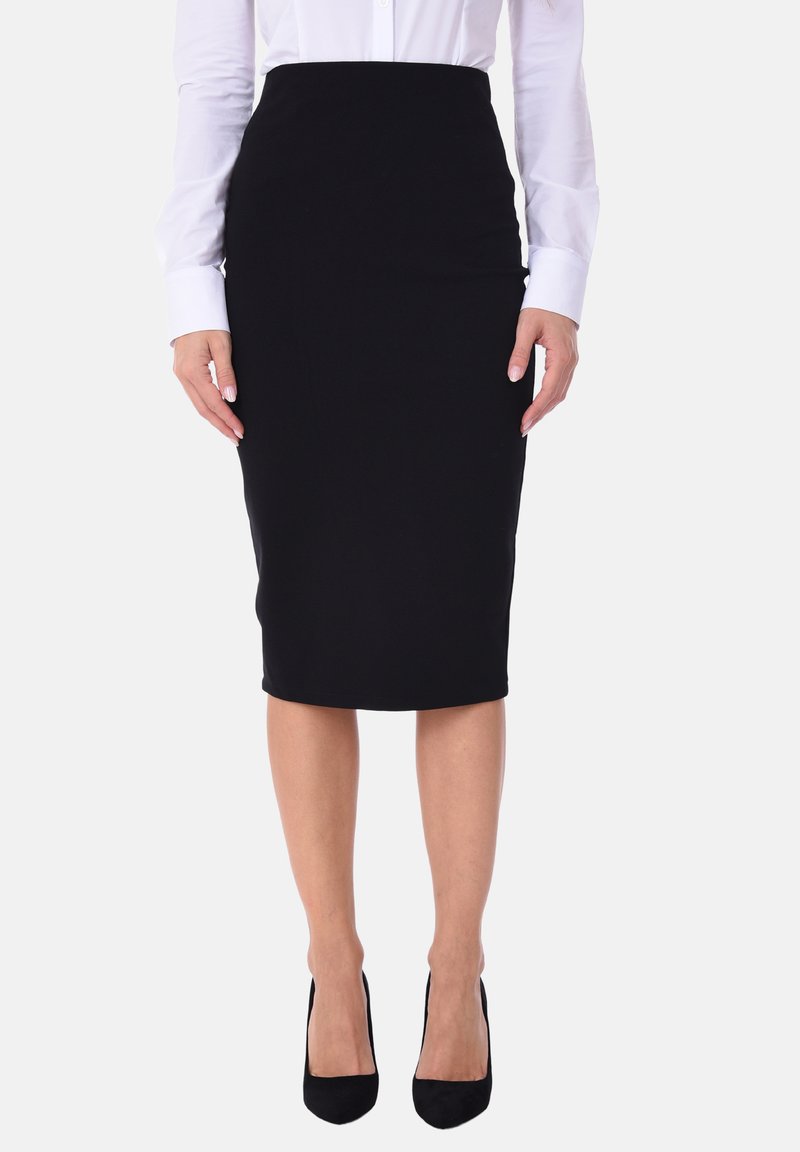 Gonna nera a matita realizzata in materiale elastico, design aderente, lunghezza al ginocchio, abbinata a una camicia bianca con bottoni e tacchi neri.