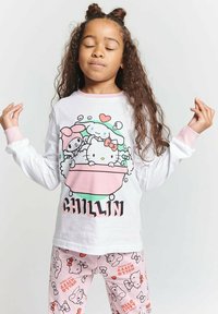 White long-sleeve shirt with cartoon graphic and pink accents; pink pajama pants with repeating Hello Kitty patterns.