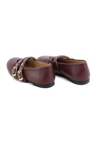 Zapatos de cuero burdeos con correas de doble hebilla, tacón bajo, punta redonda y acabado liso. Presenta acentos decorativos de hardware dorado.