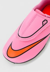 Roosa spordijalgpadi oranži Nike swoosh'i, mustade ääristustega ja Velcro kinnitusega.