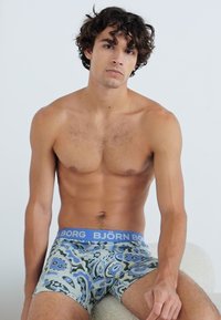 Boxer briefs masculinos com um padrão paisley azul e multicolorido, apresentando uma cintura elástica com o logo "BJÖRN BORG" e um ajuste justo.