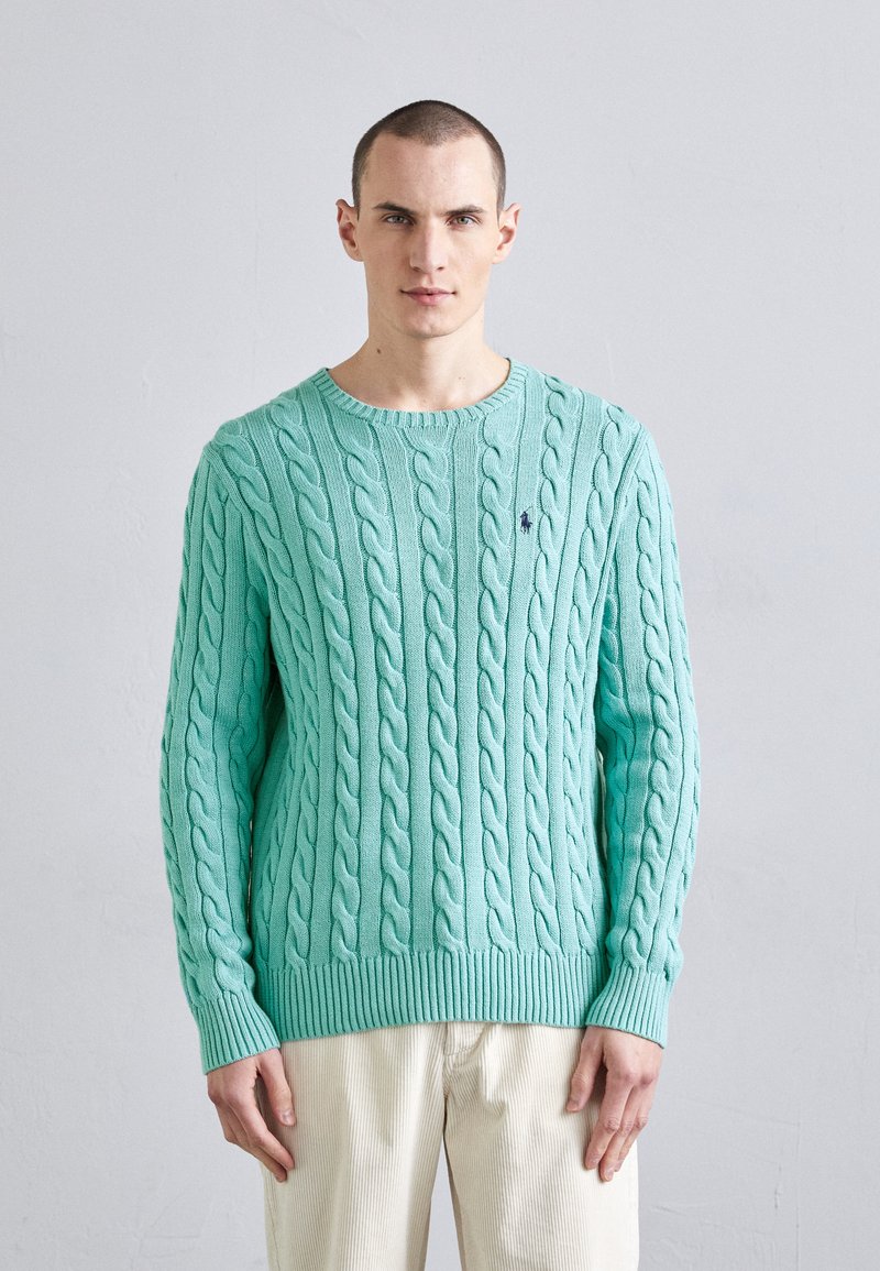 Pull en maille torsadée vert menthe avec un col rond côtelé. Présente des détails texturés et un petit logo sur la poitrine.