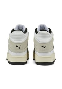 Baskets Puma en suede gris et cuir blanc, accents noirs, col rembourré et détail texturé au talon. Semelle extérieure plate en caoutchouc noir.