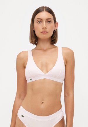 Bralette rosa chiaro con scollatura a V, spalline larghe e texture a costine. Presenta un piccolo logo verde sul lato sinistro.