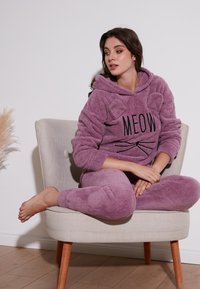 Îmbrăcăminte de lounge mov, pufoasă, cu un design cu pisici, având glugă și urechi. Costumul include un top cu textul "MIAU" și pantaloni asortați.