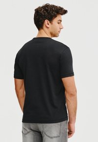 Czarny t-shirt z krótkim rękawem wykonany z bawełny, z okrągłym dekoltem i gładką, równą fakturą. Brak widocznych wzorów lub akcentów.