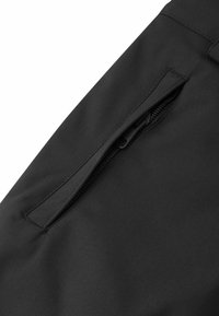 Pantalón de tela negra con un bolsillo con cremallera en el lado derecho, textura suave y diseño sin costuras sin costuras visibles.