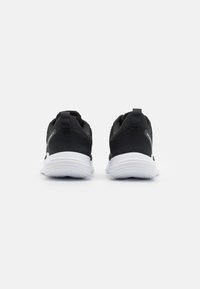 Pantofi sport negri cu un material texturat pe partea superioară, talpă albă și taburi de călcâi întărite. Prezintă branding minim pe laterale.