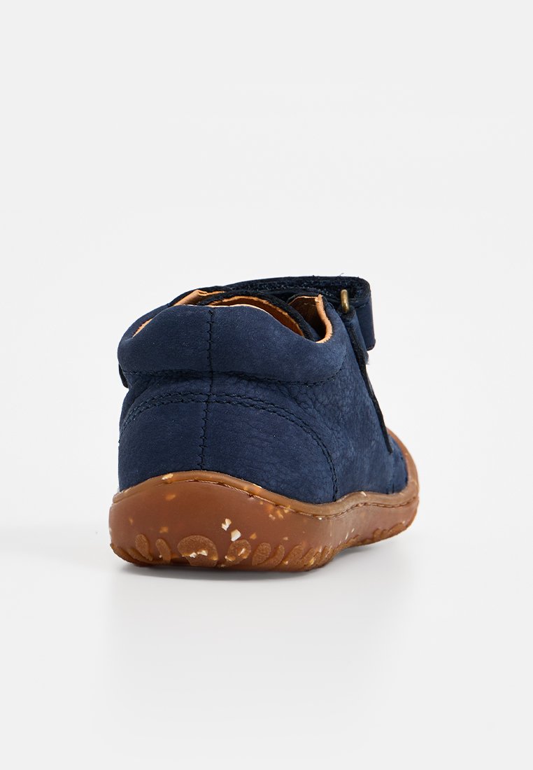 Marineblaue Kinderschuhe mit einem weichen, strukturierten Obermaterial und braunen Akzenten. Sie verfügen über eine flexible Gummisohle mit einem gemusterten Profil für besseren Grip.