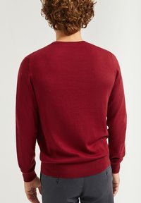Bordowy sweter dzianinowy z długim rękawem, z prążkowanymi mankietami i dołem, charakteryzujący się gładką teksturą i klasycznym okrągłym dekoltem.